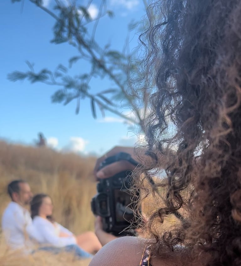 a woman taking a picture of a man in a field