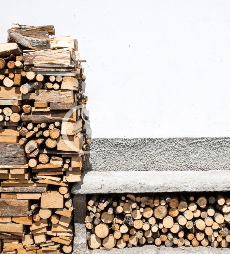 pile rangée de bûches avec un mur blanc en fond