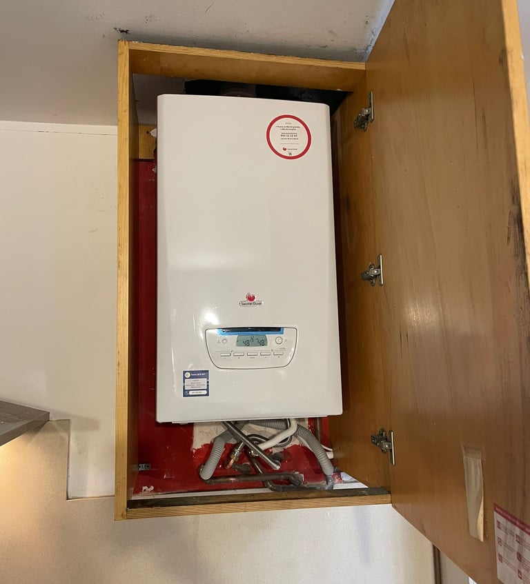 a white tankless water heater with a red and white sign