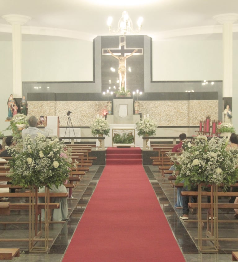 Cerimônia de casamento em uma igreja com tapete vermelho no corredor, arranjos de flores brancas e c