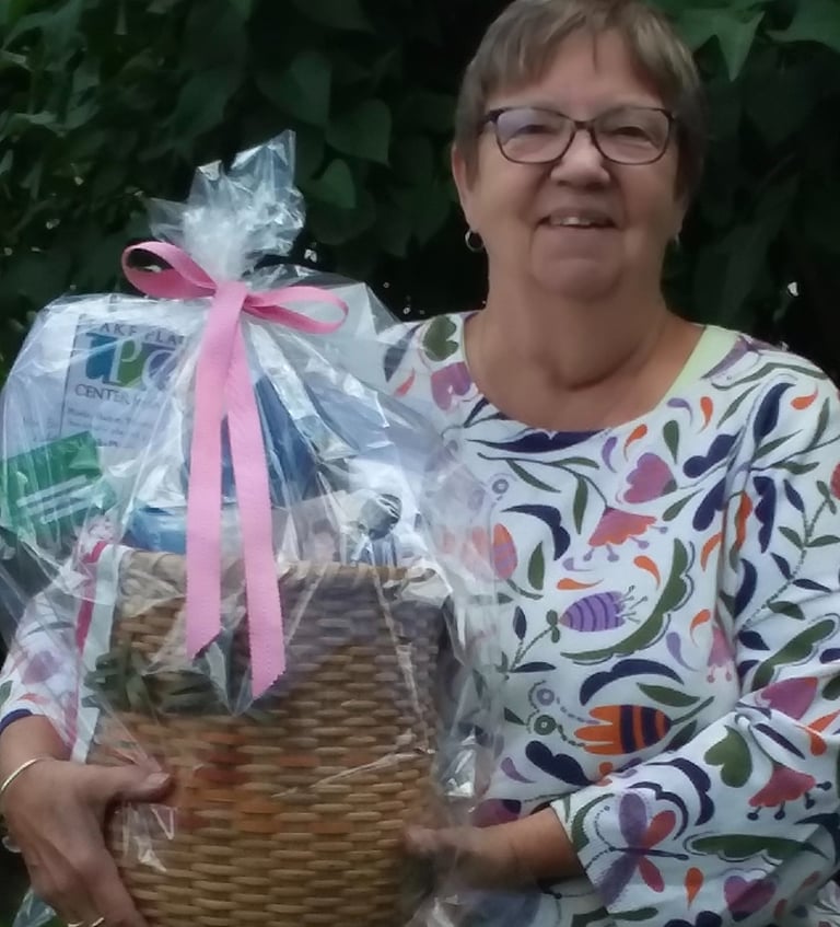 Photo of a smiling woman holding a gift basket used to raffle and raise money for the club