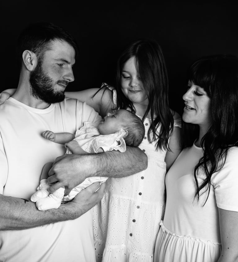 a man and woman holding a baby in a black and white photo