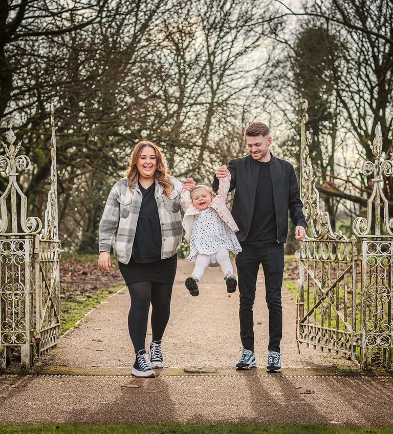 a man and woman holding a baby in a park
