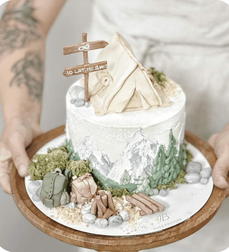 a person holding a cake with a mountain scene