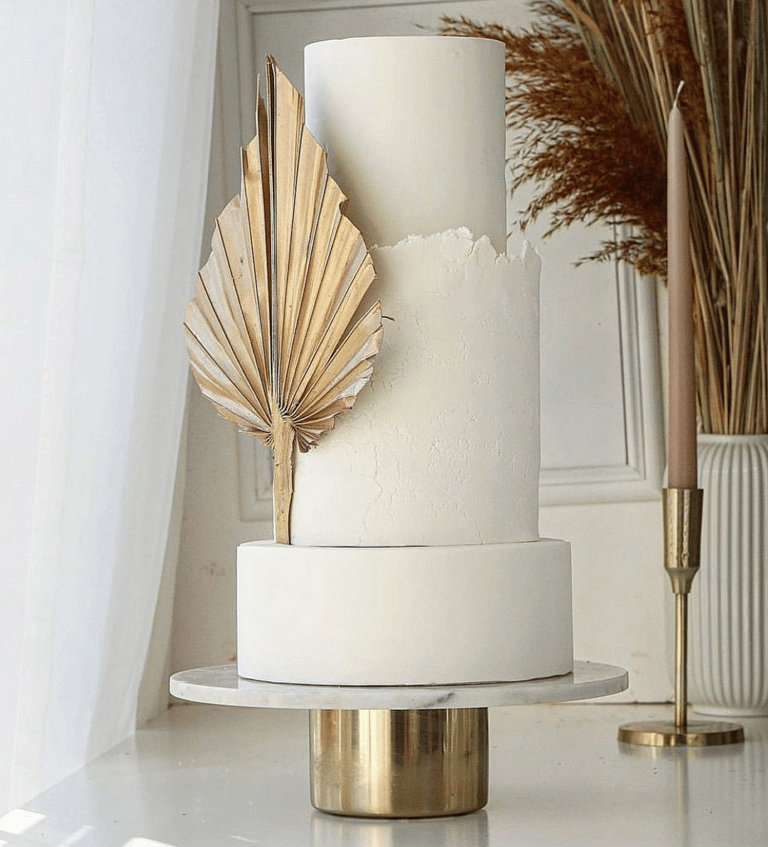 a white cake with a gold leaf decoration