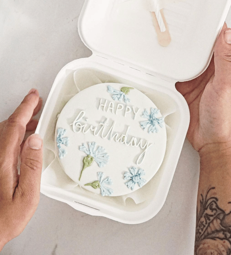 a person holding a cake with a happy birthday cake