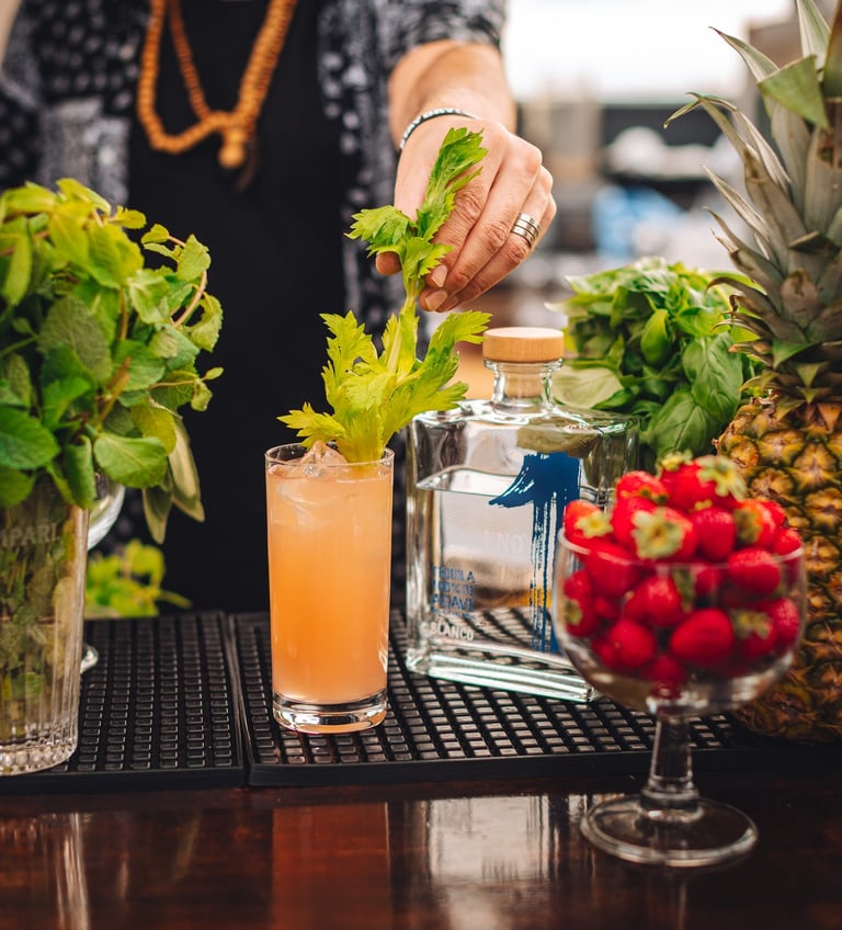 a man is preparing to make a cocktail on a bar with celery leaf and a bottle of uno tequila blanco