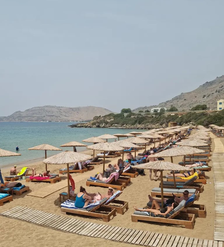 a beach with many people sitting on lounge chairs
