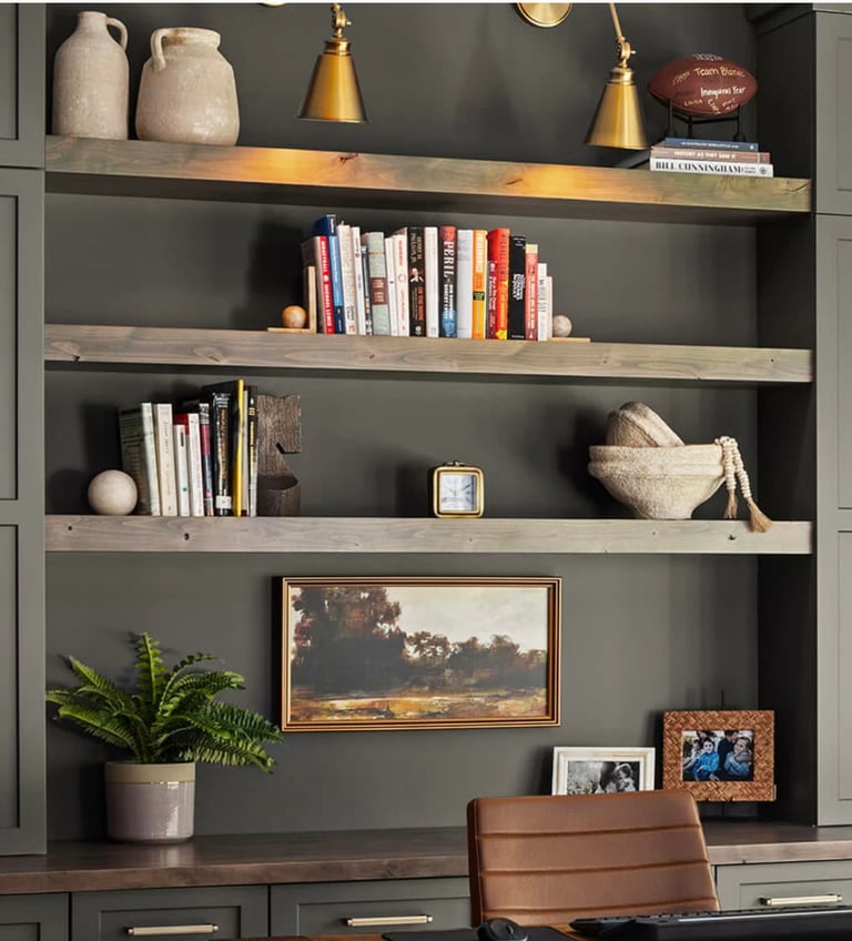 Dark gray shelving unit styled with books, ceramic vessels, brass pendant lights, framed artwork, an