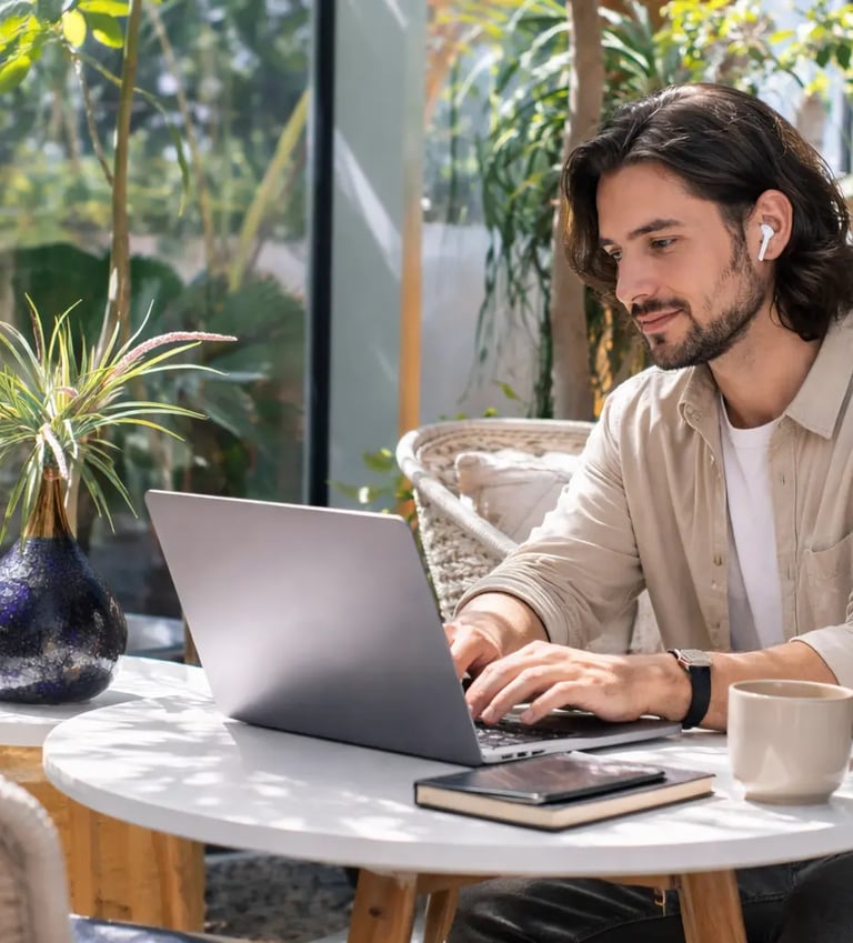 a man sitting at a table with a laptop and a cup of coffee