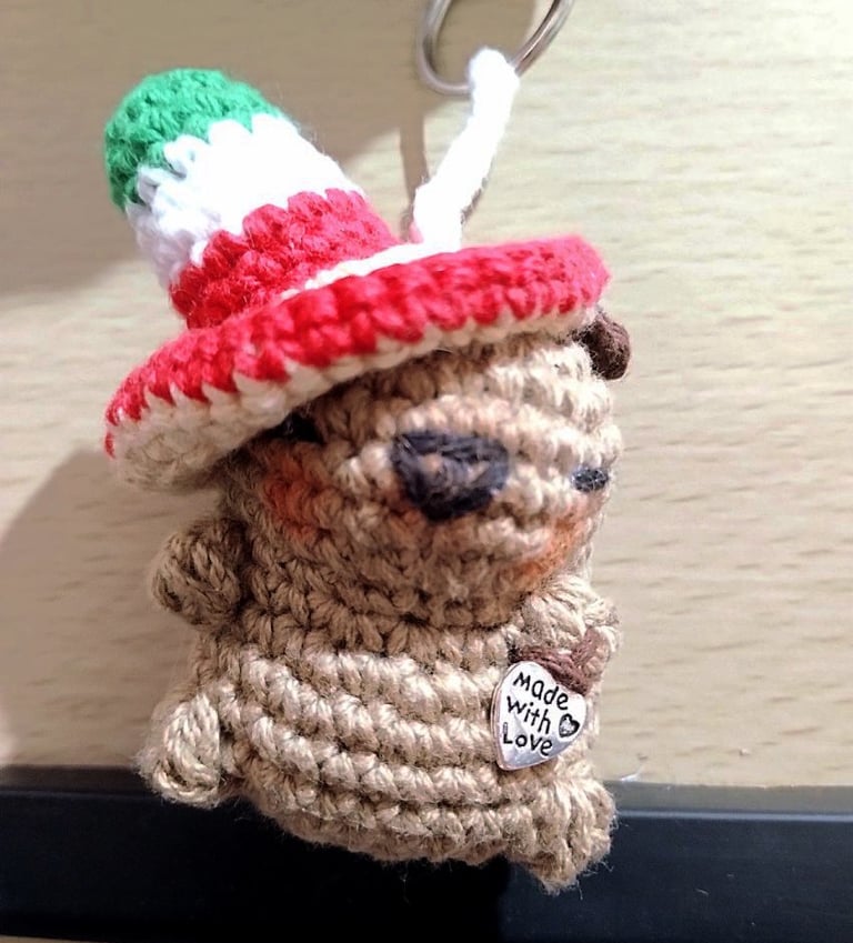 Llavero de capibara marrón tejido a mano en crochet, con un sombrero mexicano verde, blanco y rojo.