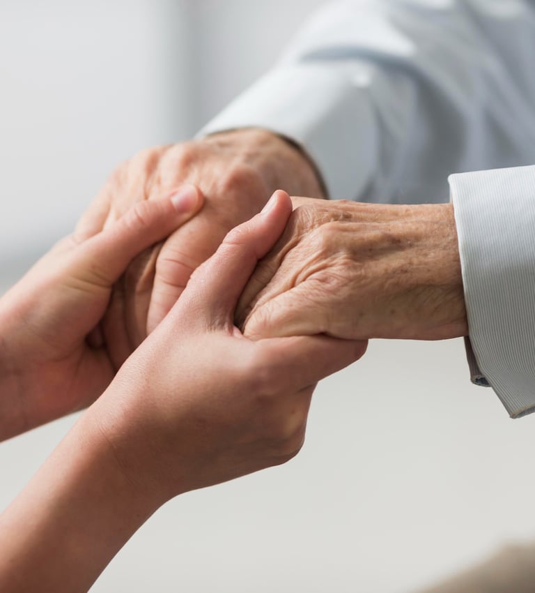 a woman caregiver holding a senior man's hand