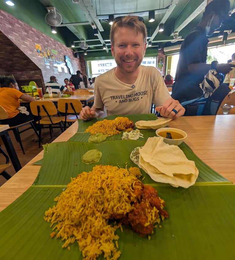 Don enjoying a traditional South Indian biryani meal served on a banana leaf in a busy restaurant.