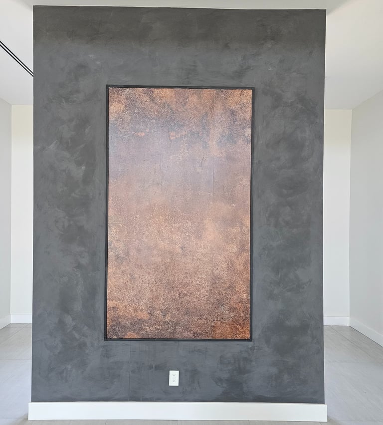 Bold black limewash wall with a rectangular copper wallpaper inset, combining textured depth with warm metallic contrast