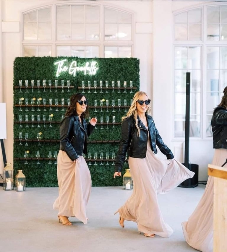 Bridesmaids walking past the grass champagne walls behind them.