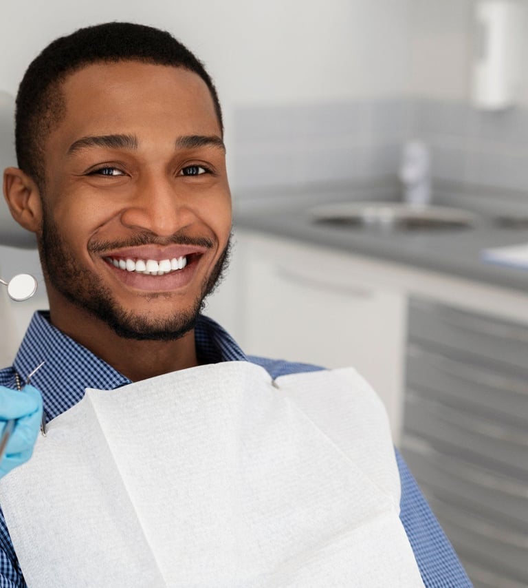 A smiling man as a dentist holds instruments nearby.