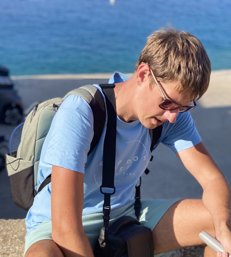 a man sitting on a ledge with a camera gear in Rhodes Greece