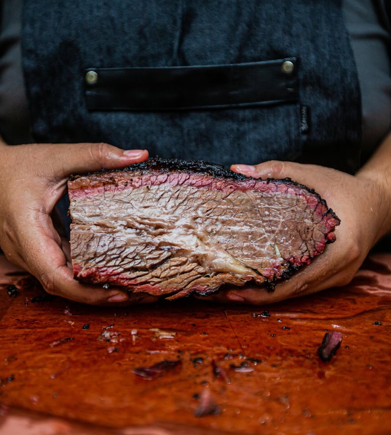pitmaster holding a smoked brisket over a cutting board