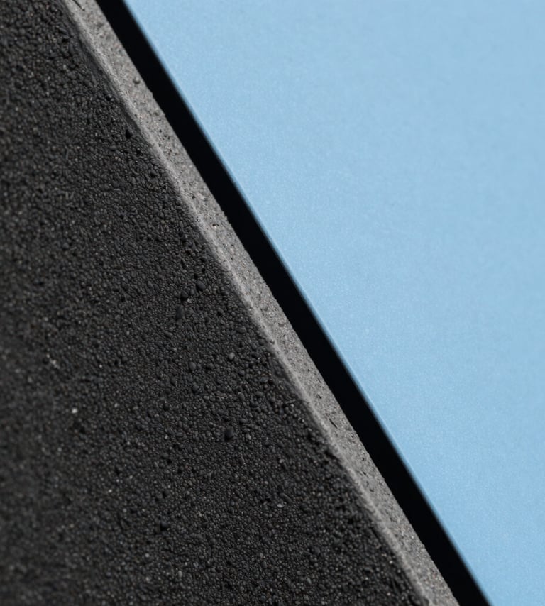 Macro photography of textured dark grey materials and a smooth baby blue surface meeting at a sharp diagonal line. The lighting creates a high-contrast, professional, and abstract look. South American architectural detail style.