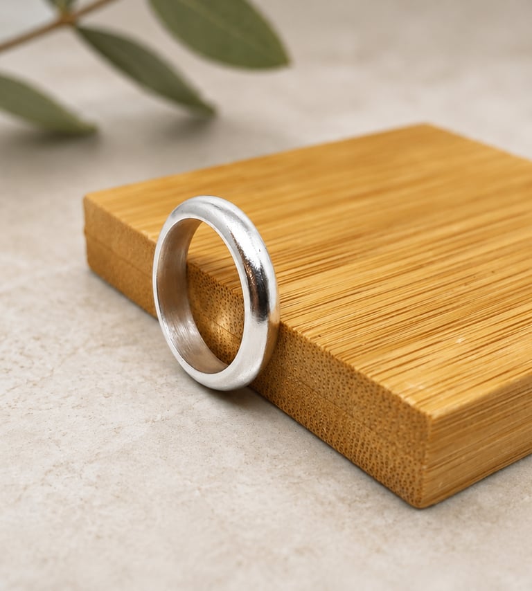 Minimalist polished satin 999 fine silver wedding band  on a bamboo display block in green leaves.