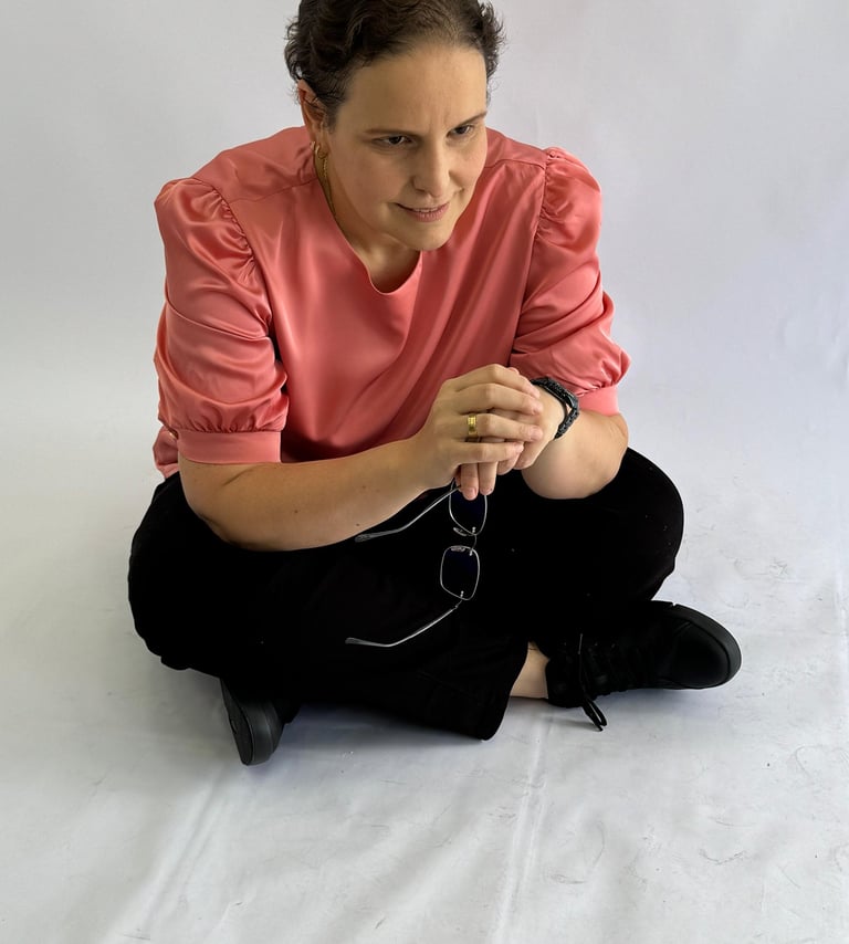 a woman sitting on a white sheet with a cell phone
