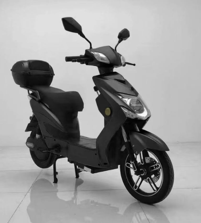 Sleek matte black electric scooter with a storage trunk parked on a white floor.