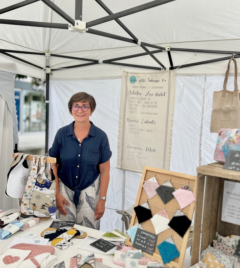 La créatrice derrière son stand sur un marché de créations artisanales