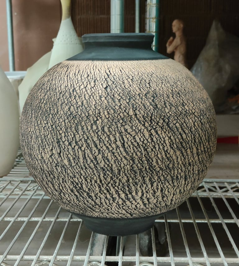 wheel-thrown moon jar with sodium silicate crack texture and black underglaze, awaiting high fire