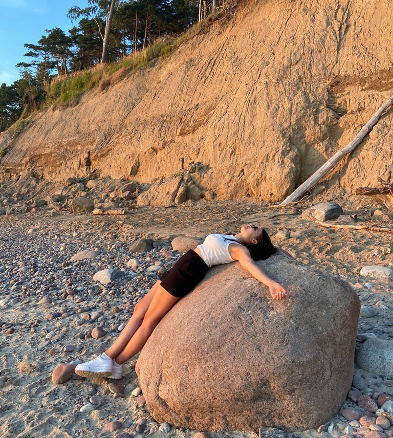A picture of a woman laying on rock on a beach