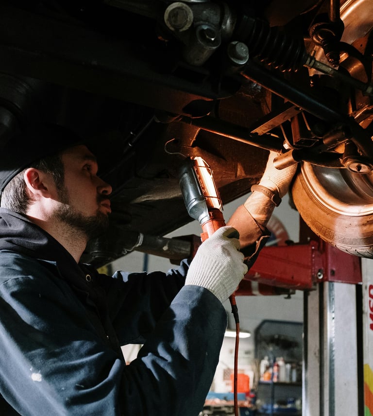 Mécanicien réalisant un diagnostic automobile sous un véhicule en atelier