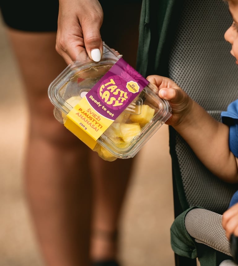 vaikas ir mama laiko pjaustytų ananasų indelį