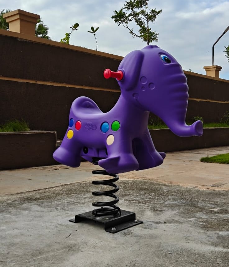Purple elephant spring rider on a playground with a cloudy sky background.