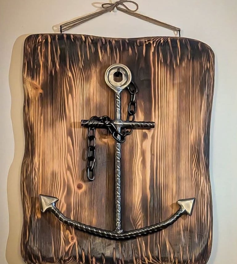 Hanging wall decor featuring a handcrafted metal anchor on a charred wood plaque.