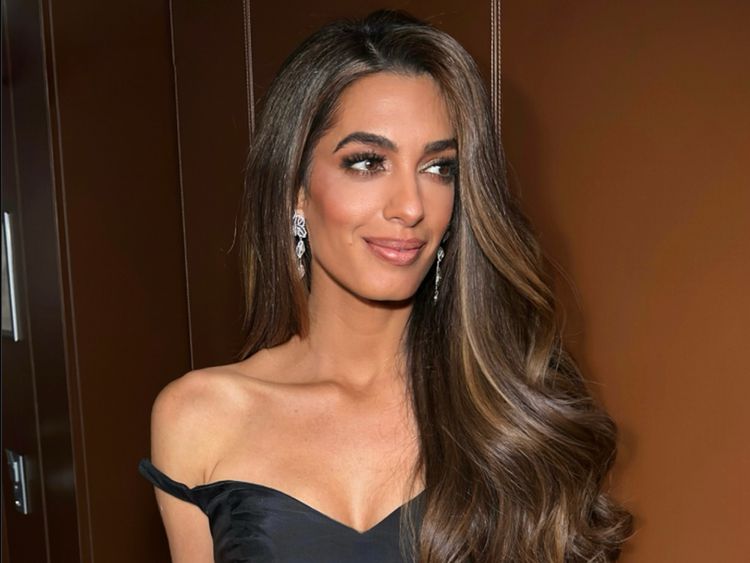 a woman in a black dress with long hair and earrings