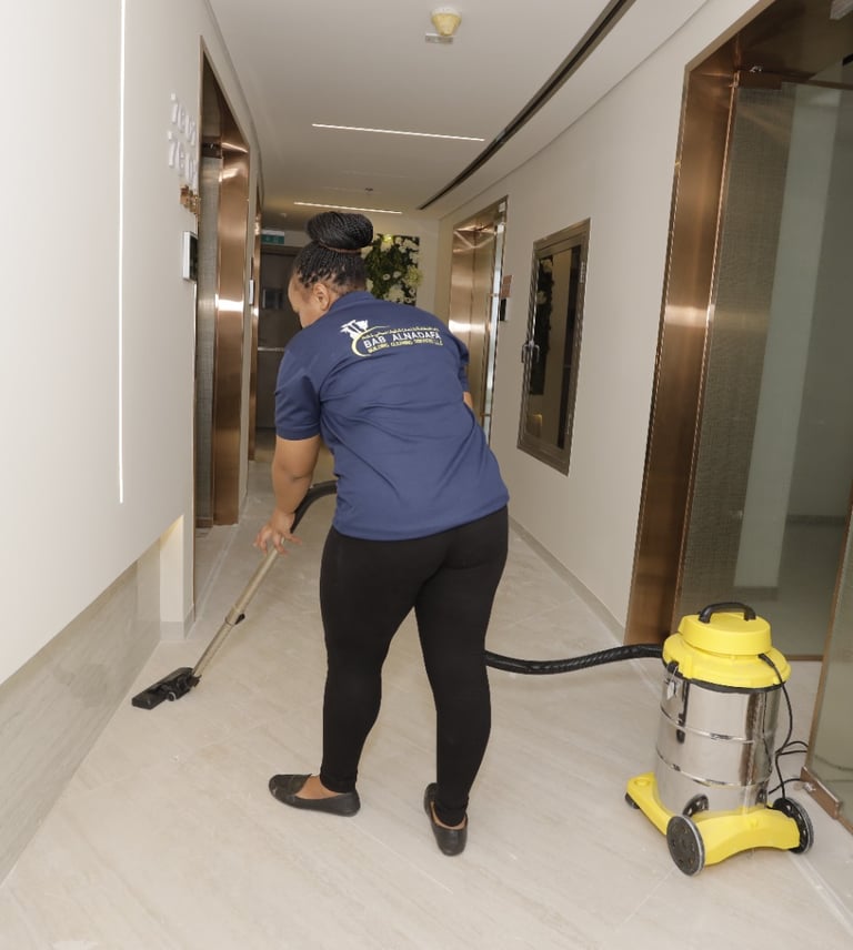a cleaner in a blue shirt is cleaning a hallway