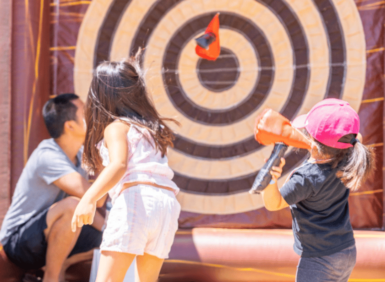 a young girl is playing with a blow up in a bouncer carnival event planner carnival games
