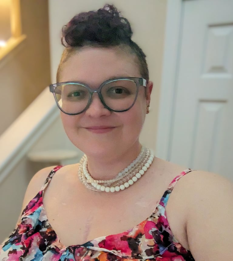 Picture of Megan, a smiling woman with a blue mohawk and pearls.