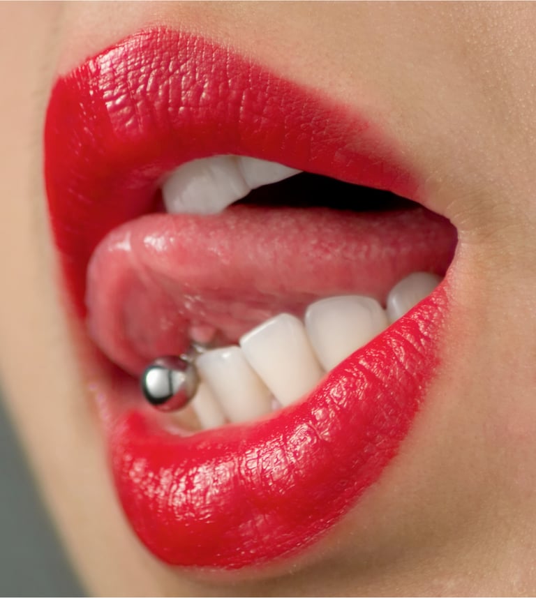 Close-up of red lips and white teeth with a silver barbell tongue piercing.