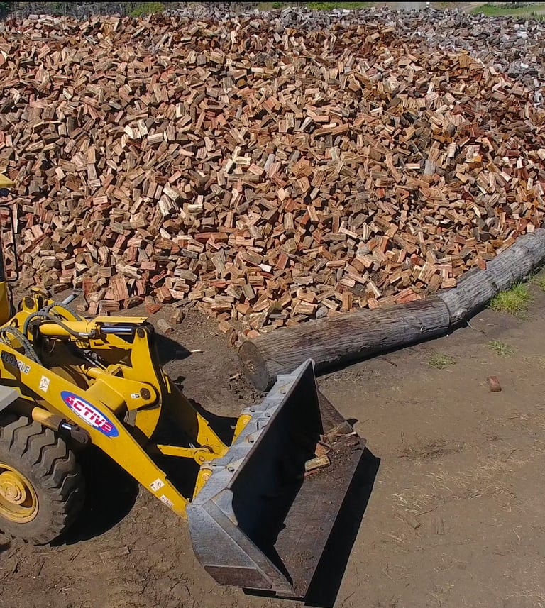 Loader in front of seasoned firewood