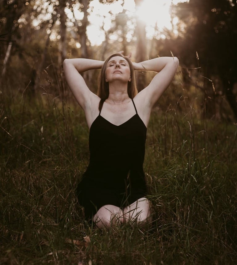a woman in a black bathingsuit sitting on the grass