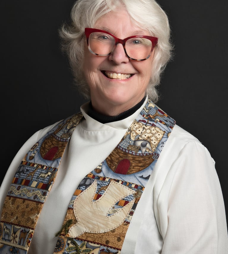 a woman in a clergy outfit and red glasses smiling