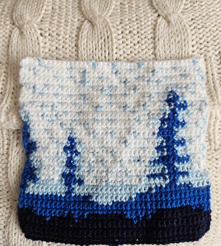 a crochet blue and white tapestry on a white pillow
