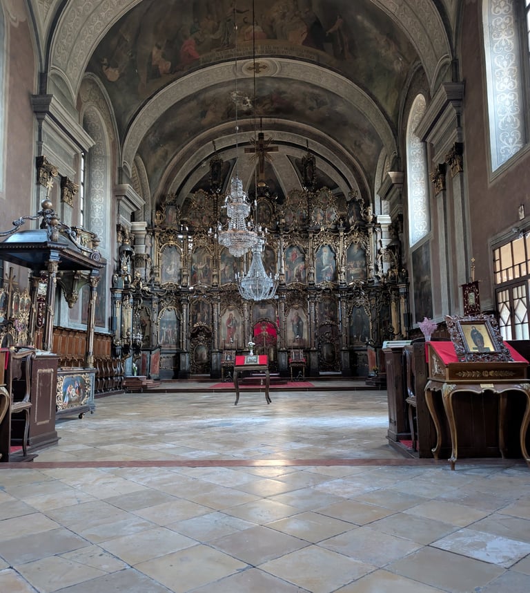 The interior of the Church of Almashka with ornate wood framed wall frescos and a painted ceiling.