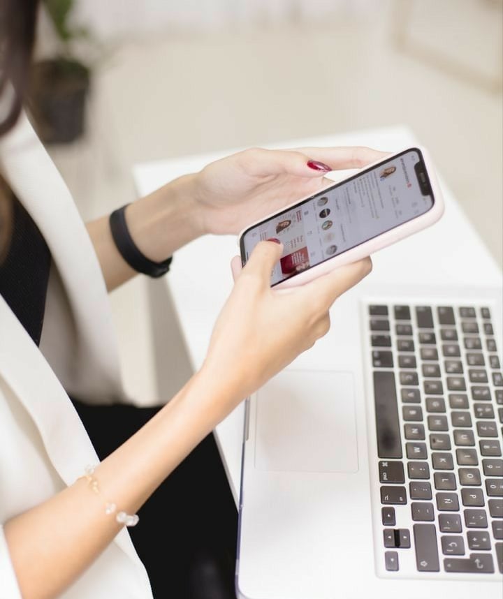Mujer profesional usando un teléfono inteligente mientras trabaja en una computadora portátil