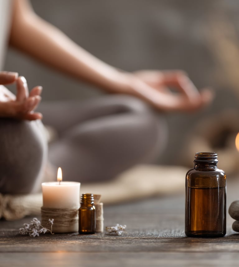 Meditative scene with candles, essential oils, and a person sitting in a grounding pose