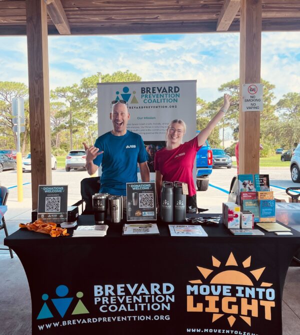 two people standing at information booth hands up and smiling