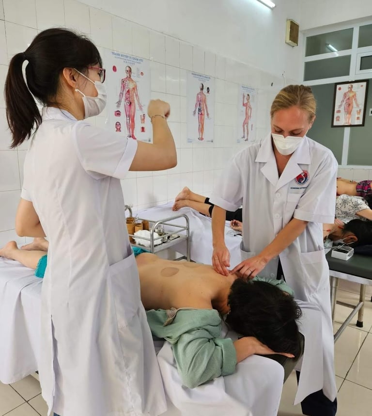 Professional acupuncturists in a clinic performing traditional acupuncture therapy on a patient's back.