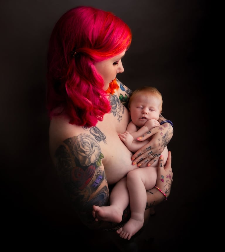tattooed redhead woman carrying a baby