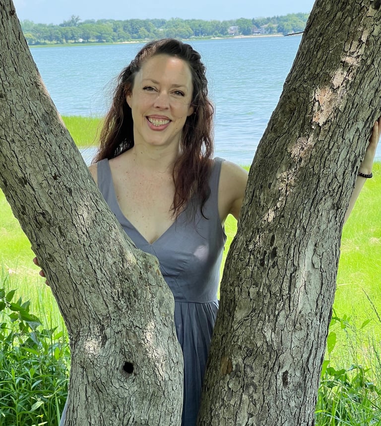 a woman in a dress standing in front of a tree