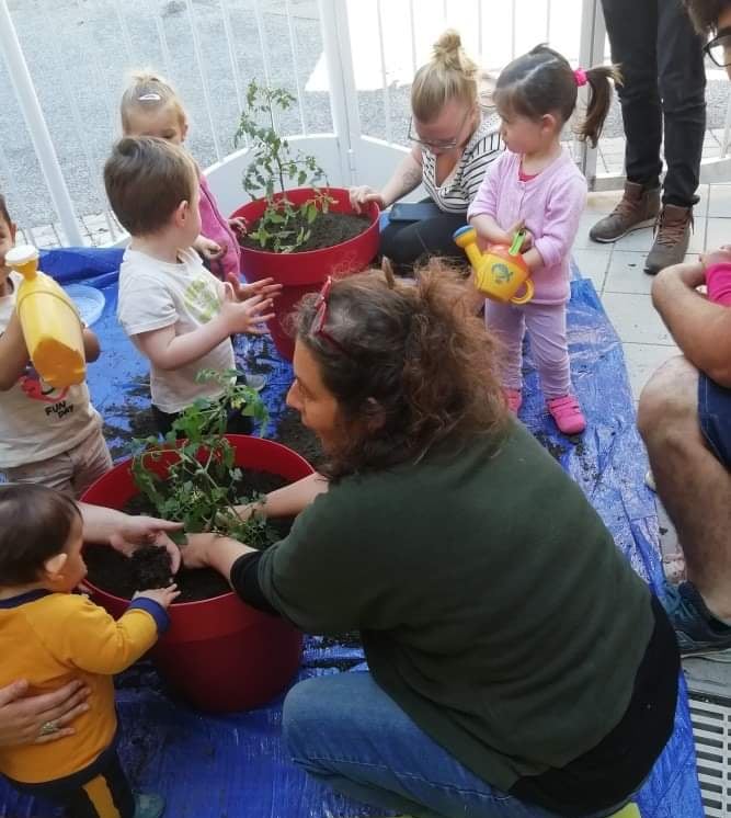 animatrice sensibilisant un groupe d'enfants par la création d'un potager et bacs de cultures